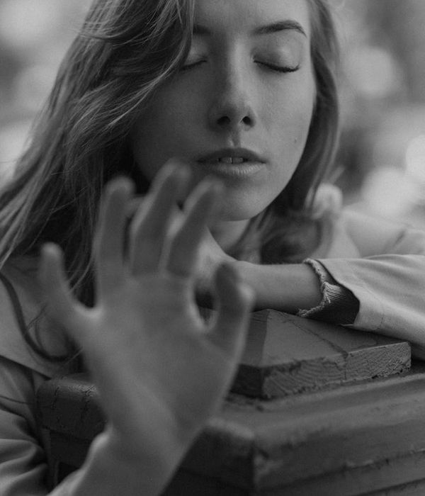 Woman in a calm yoga pose in a dark room with mint light.
